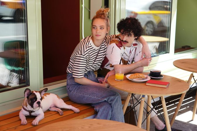 Casal numa esplanada de café com um buldogue francês deitado no banco ao lado