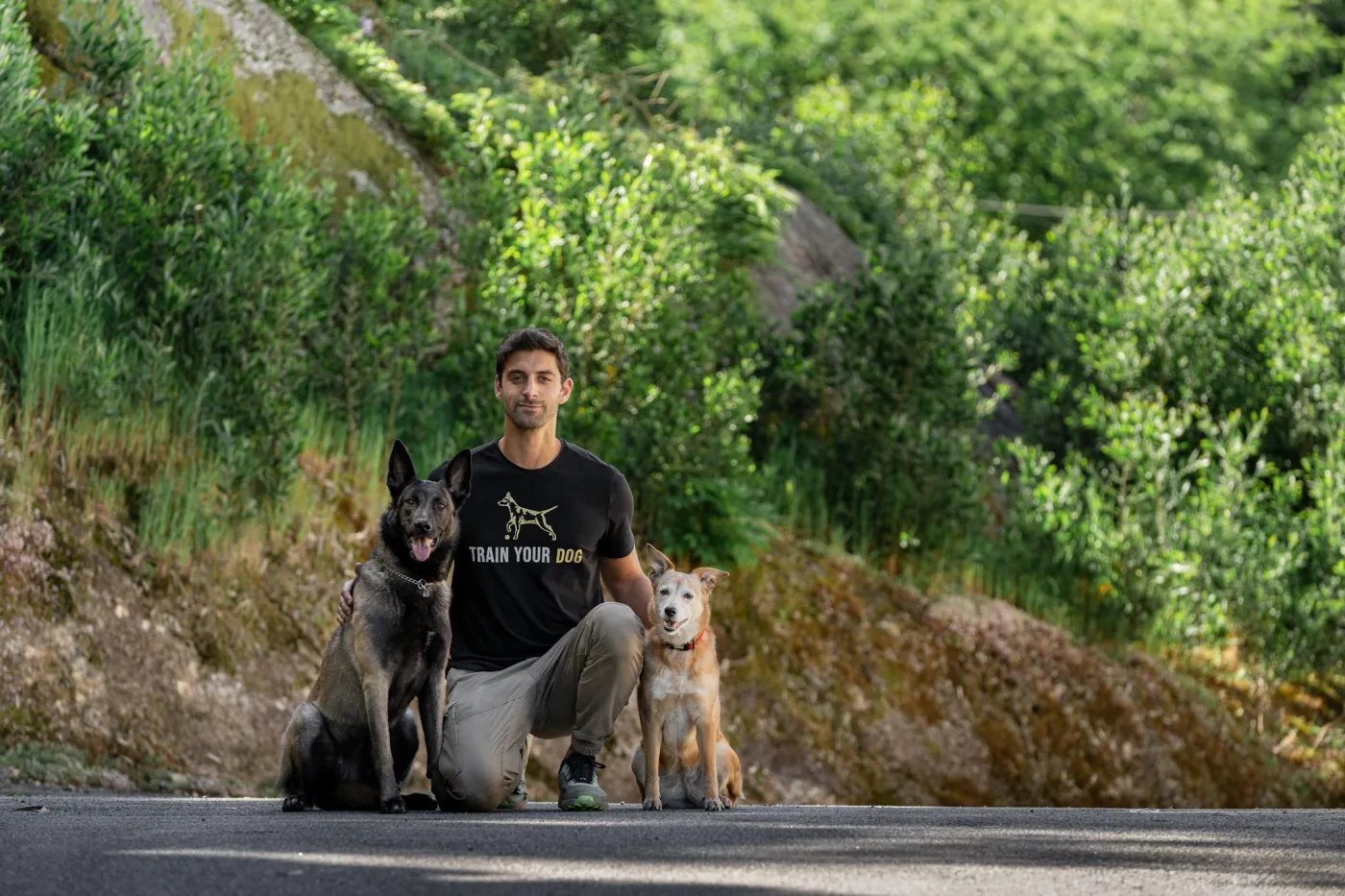Nuno Lopes agachado entre duas cadelas numa estrada